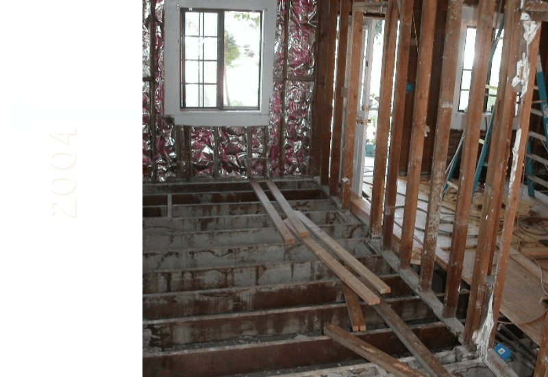 Interior of a home under renovation in 2004, featuring exposed framing and a window.