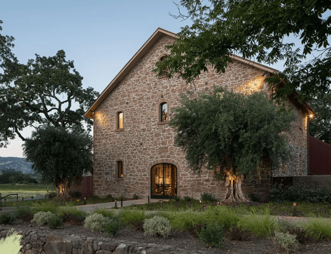 A rustic stone building surrounded by lush greenery and trees at dusk. A rustic stone building surrounded by lush greenery and trees at dusk.