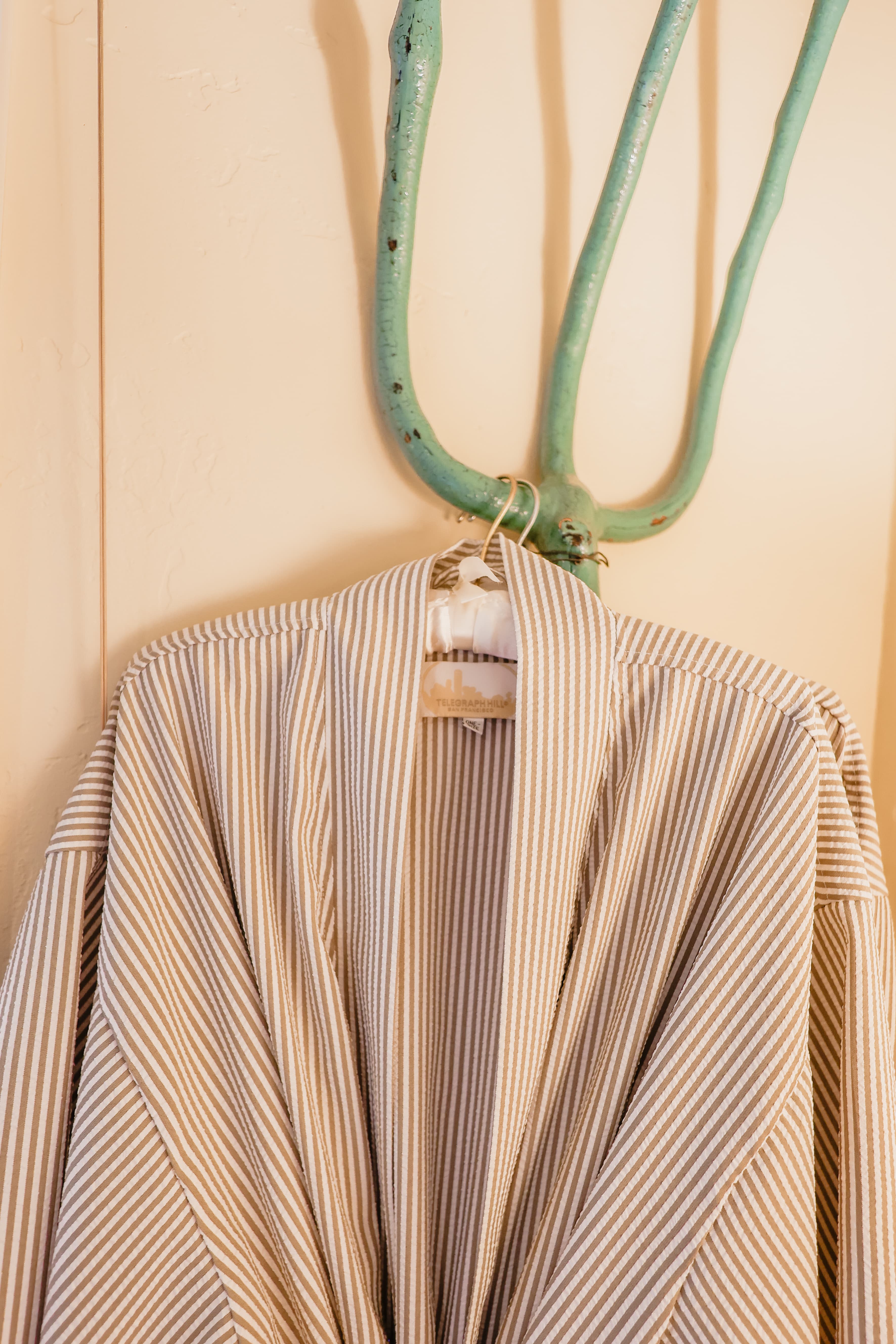 A striped garment hangs from a turquoise hook on a wall.