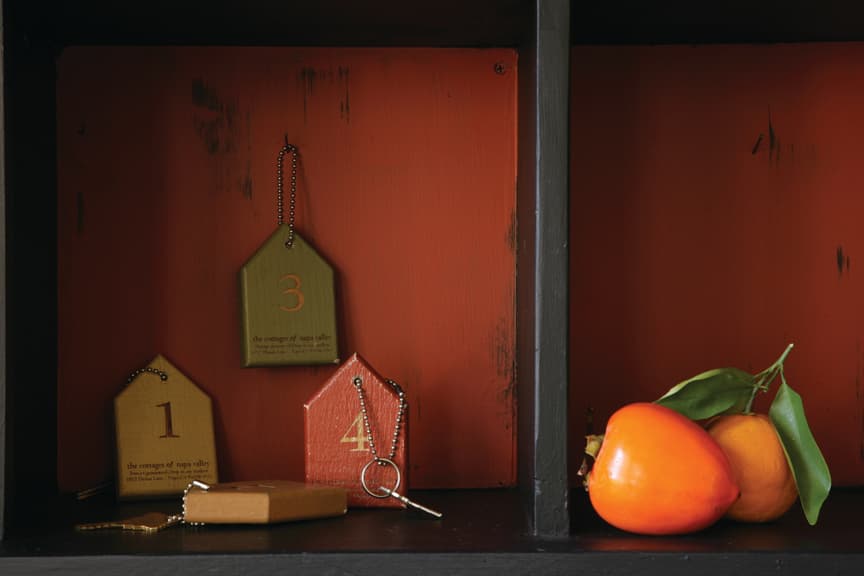A shelf displays colored tags with numbers, a brown keychain, and a persimmon fruit.
