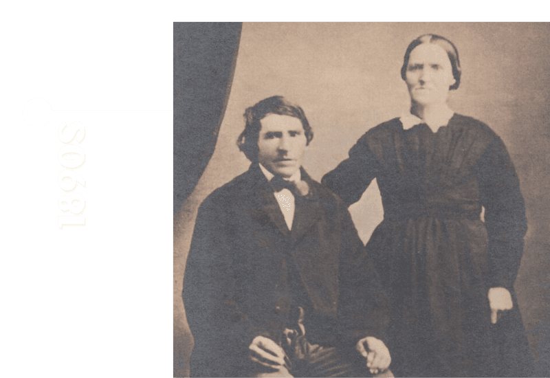 A sepia-toned photo of a man and woman posed together in 1890s clothing.